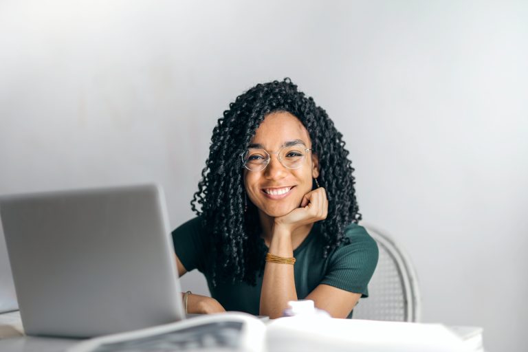 Happy female digital marketer smiling with a laptop in front of her